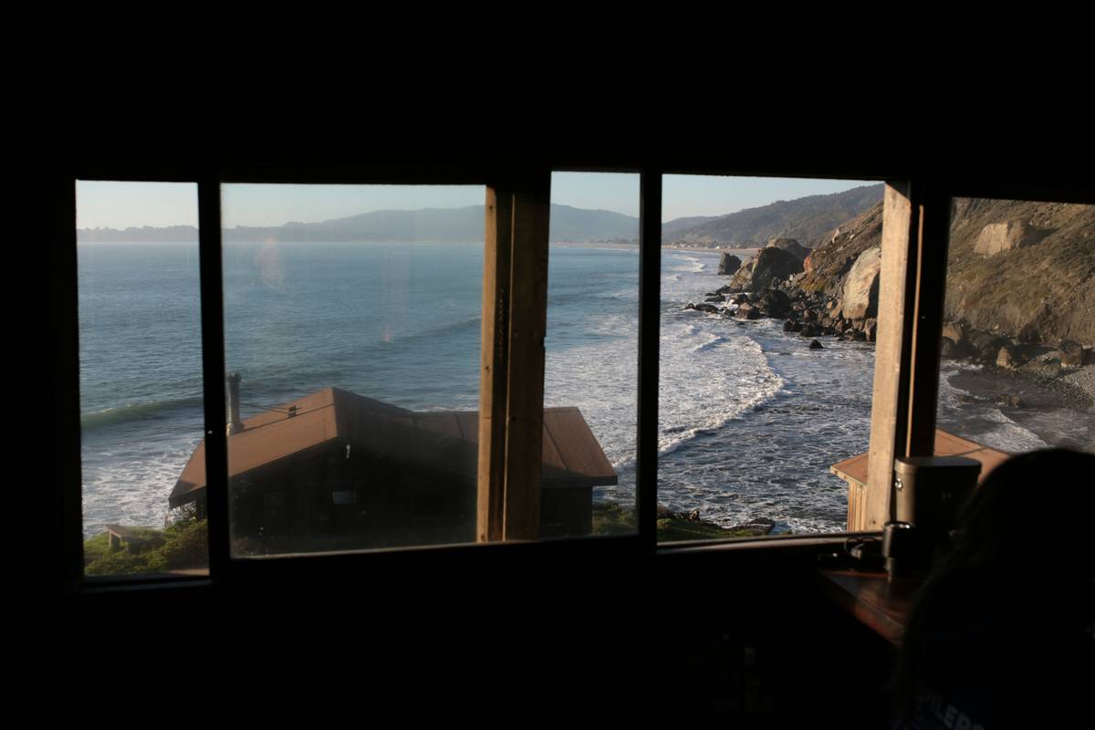 Ocean waves crash against rocky coastline seen through window.